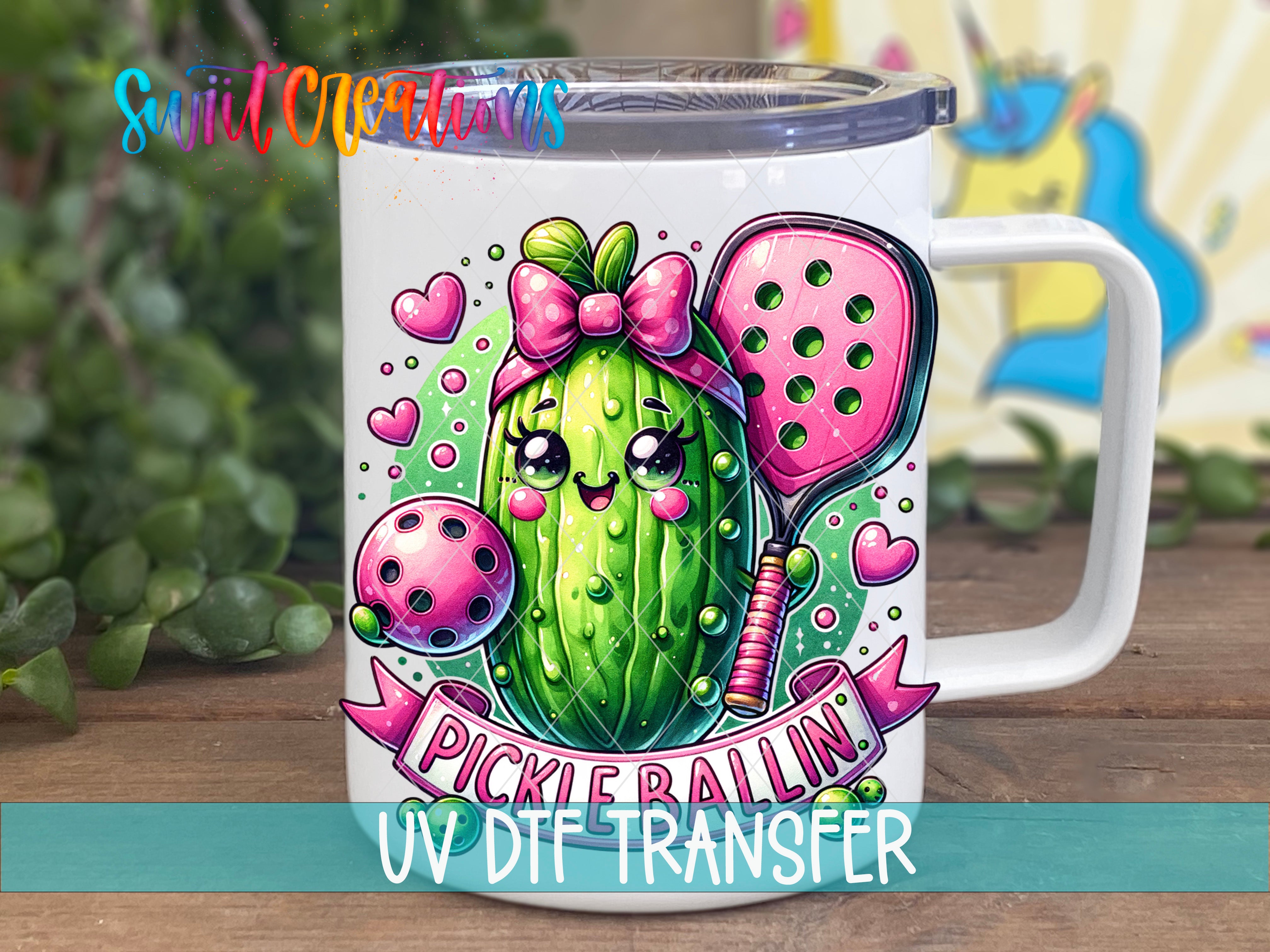 A white mug with a colorful illustration of a pickle on it, along with a ribbon that says "Pickle Ballin" and the text "UV DFT TRANSFER".