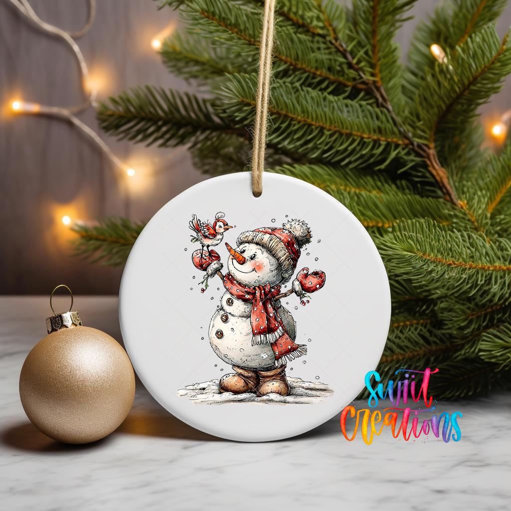 A white ceramic ornament featuring a snowman holding a bird, surrounded by Christmas lights and a pine tree.