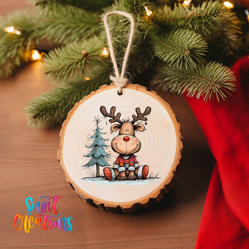 A wooden ornament featuring a smiling reindeer is hanging on a Christmas tree, surrounded by pine branches and twinkling lights.