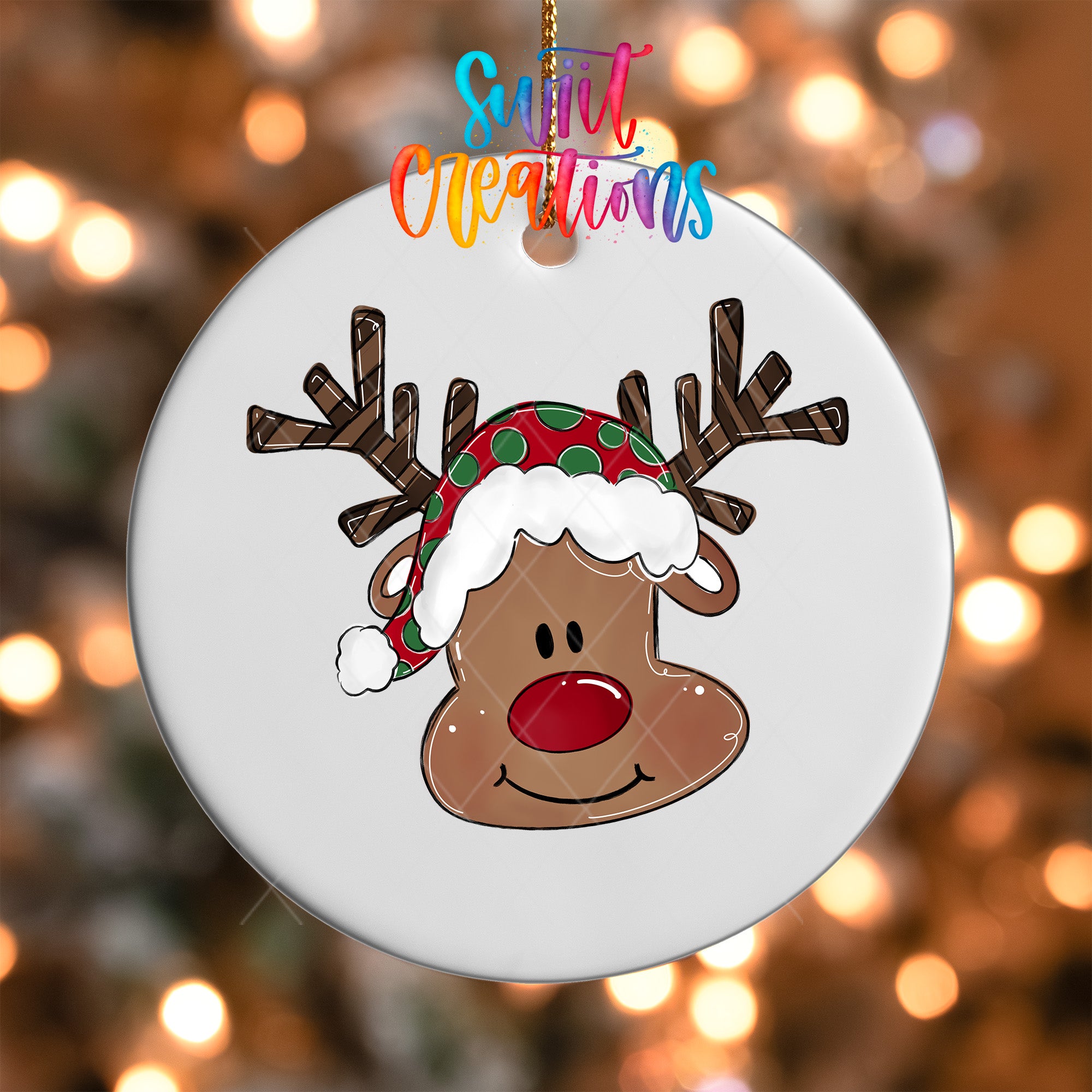 A white ornament with a cartoon reindeer wearing a Santa hat and smiling.