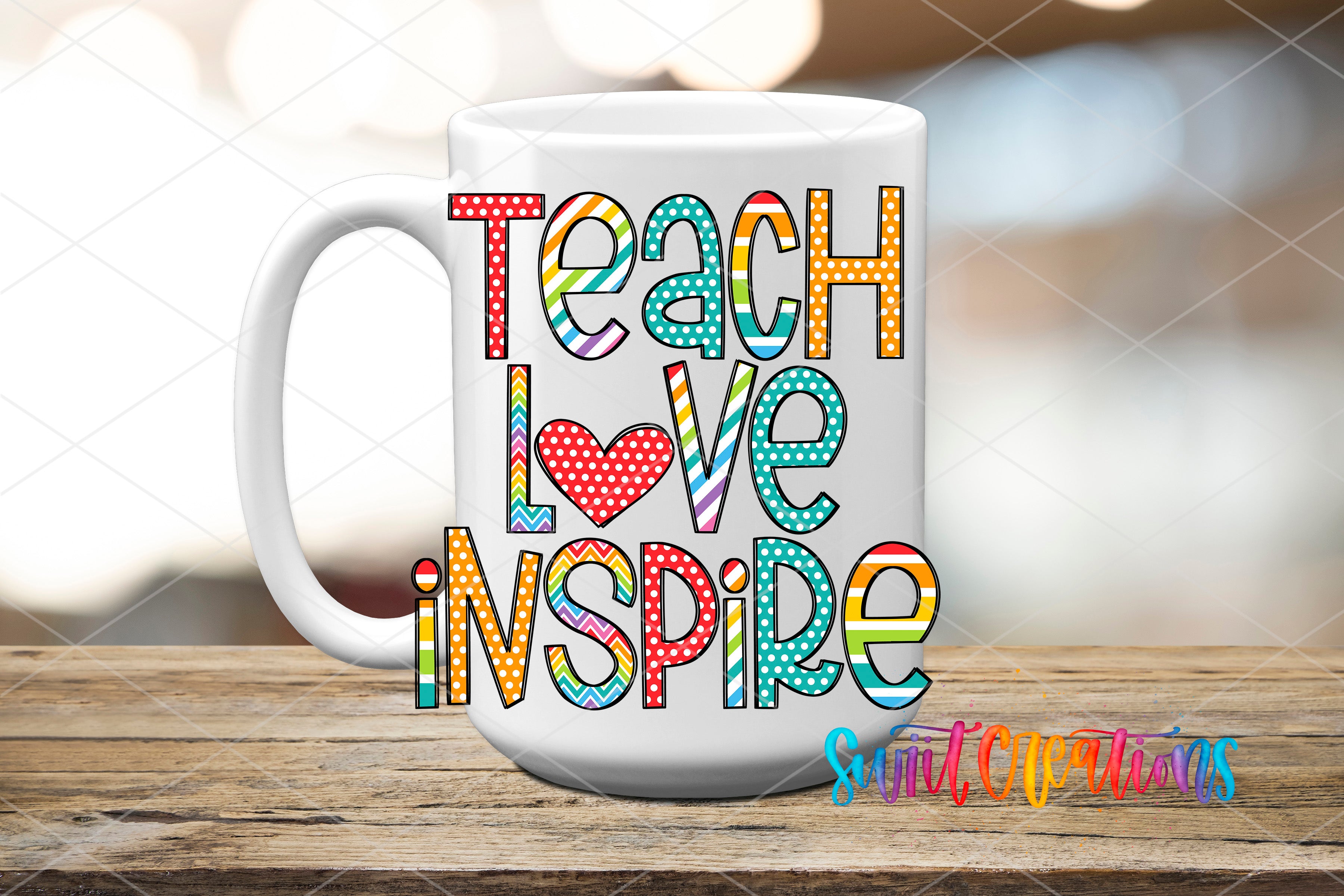 A white mug with colorful text that says "Teach Love Inspire" on it, placed on a wooden surface.