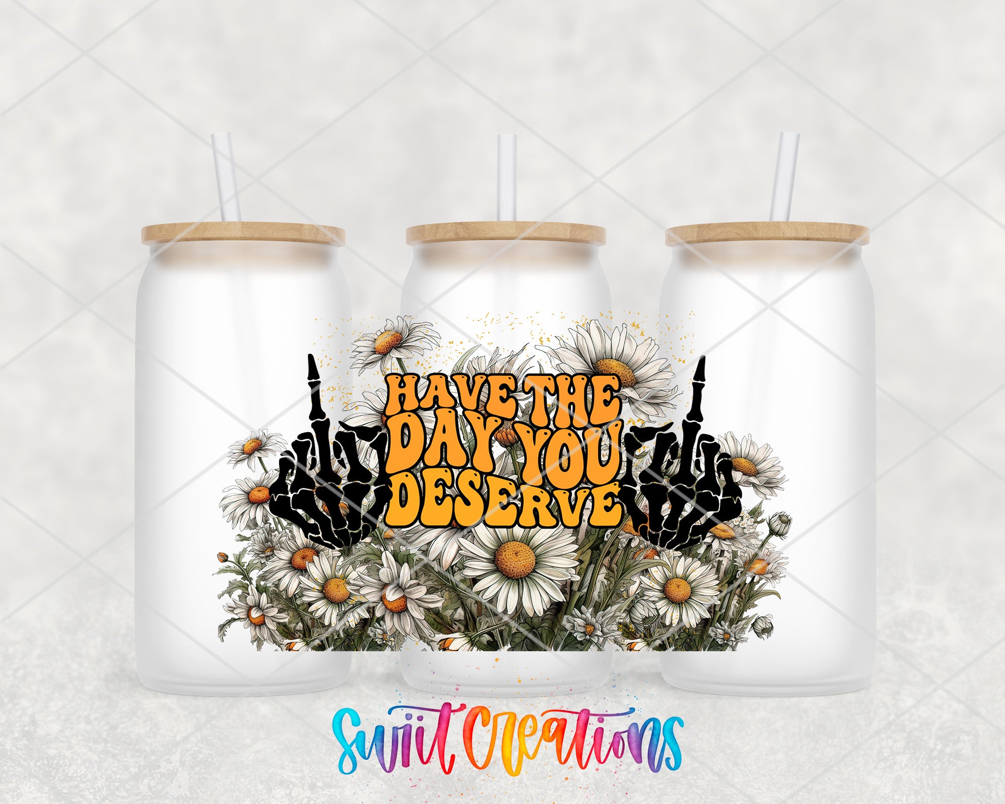 three white glass tumblers with wooden lids, each containing a straw. The tumblers are arranged in a row, and there is a colorful graphic design on the front of each tumbler. The graphic design includes a floral arrangement and the text "HAVE THE DAY YOU DESERVE" written in a stylized font.