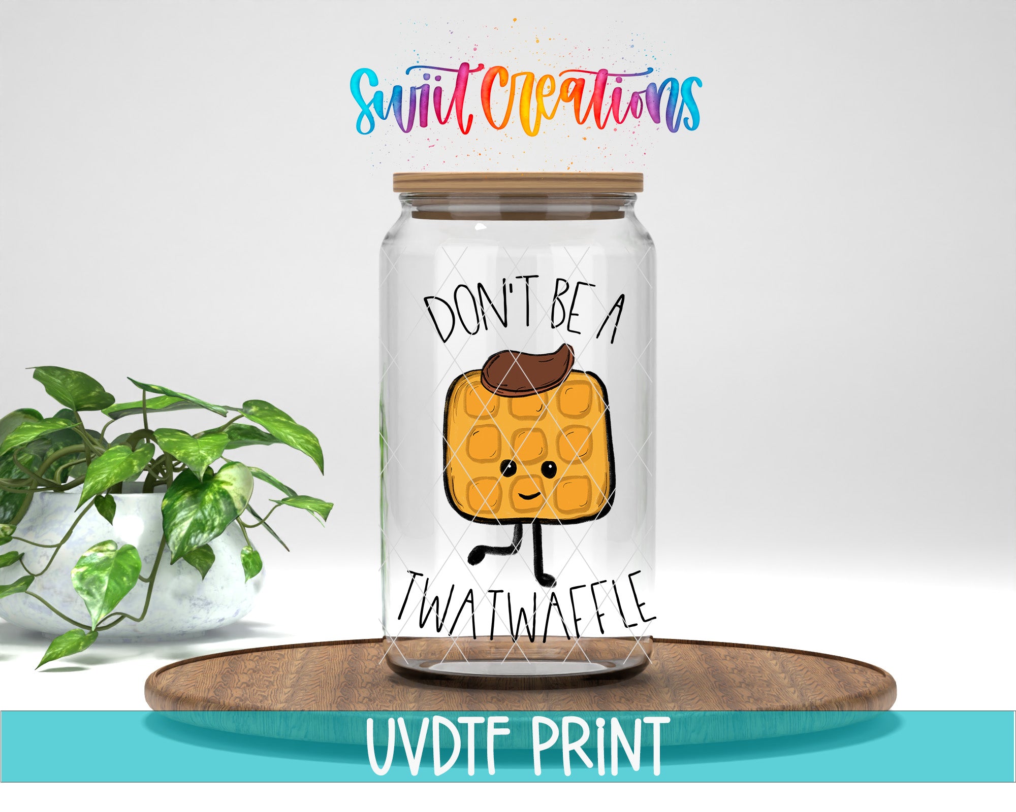 A glass jar with a cartoon image of a waffle on it, along with the text "DON'T BE A TWATWAFLE" printed on it. The jar is placed on a wooden surface, and there is a potted plant in the background.