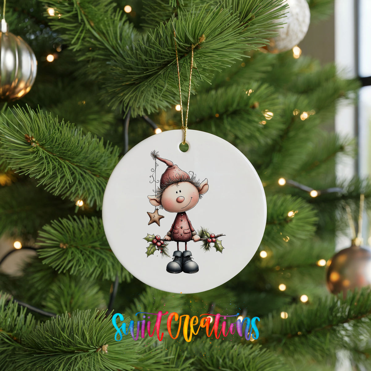 A white ceramic ornament featuring a cartoon elf holding a star and holly is hanging on a Christmas tree.
