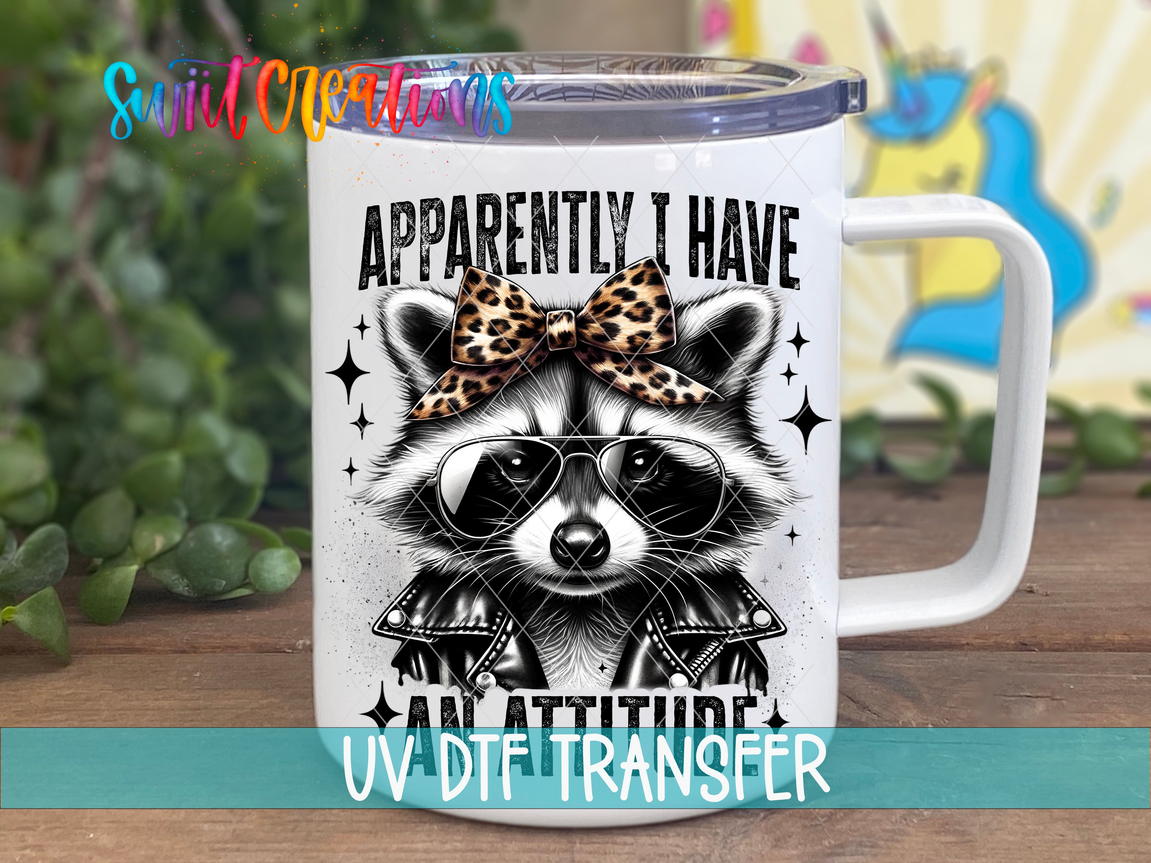 A white mug with a raccoon wearing sunglasses and a leopard print bow tie, along with the text "Approximately I Have An Attitude" printed on it.