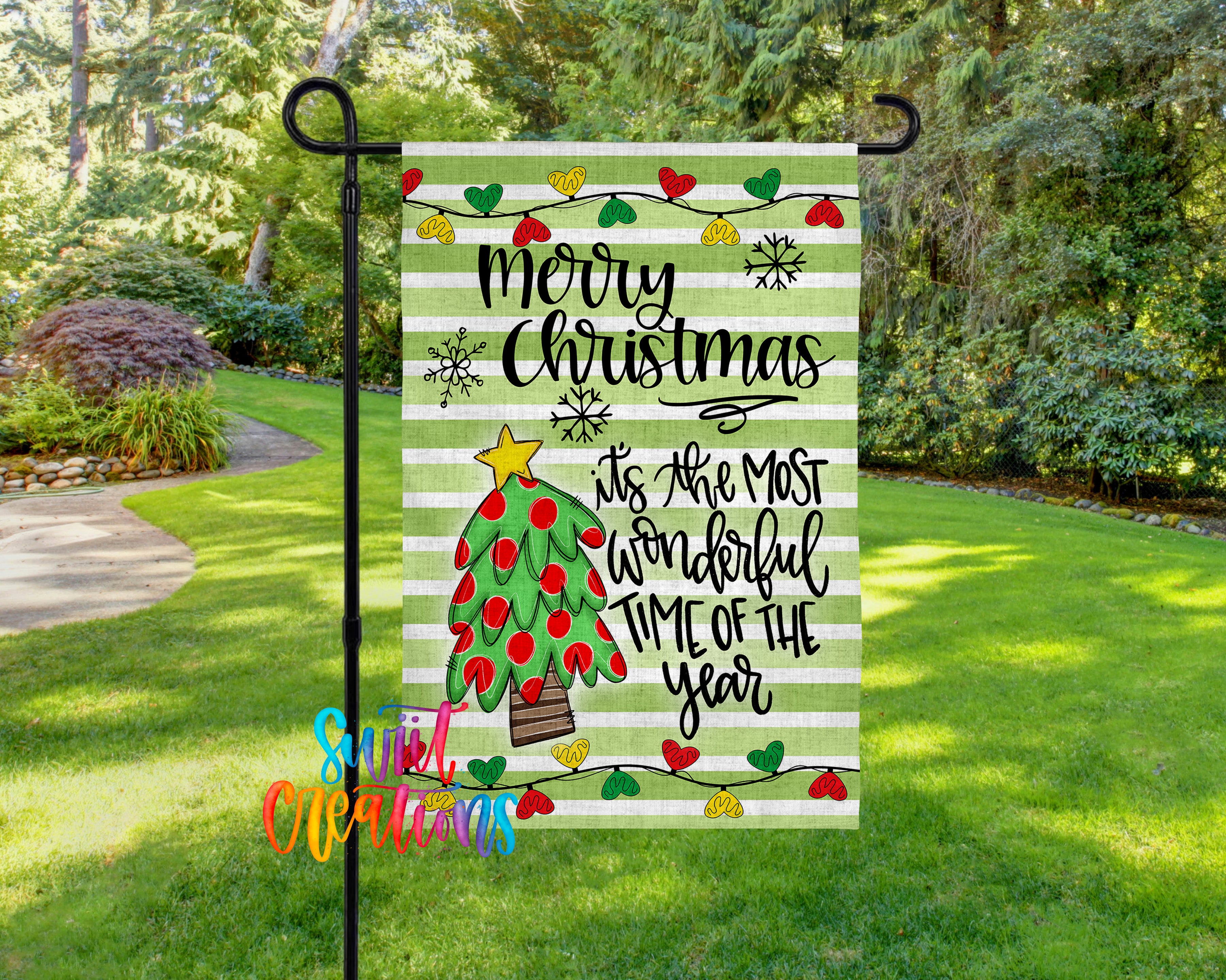 A colorful Christmas-themed flag is displayed in a grassy area, featuring a tree with red and green ornaments and a message that reads "Merry Christmas is the most wonderful time of the year".