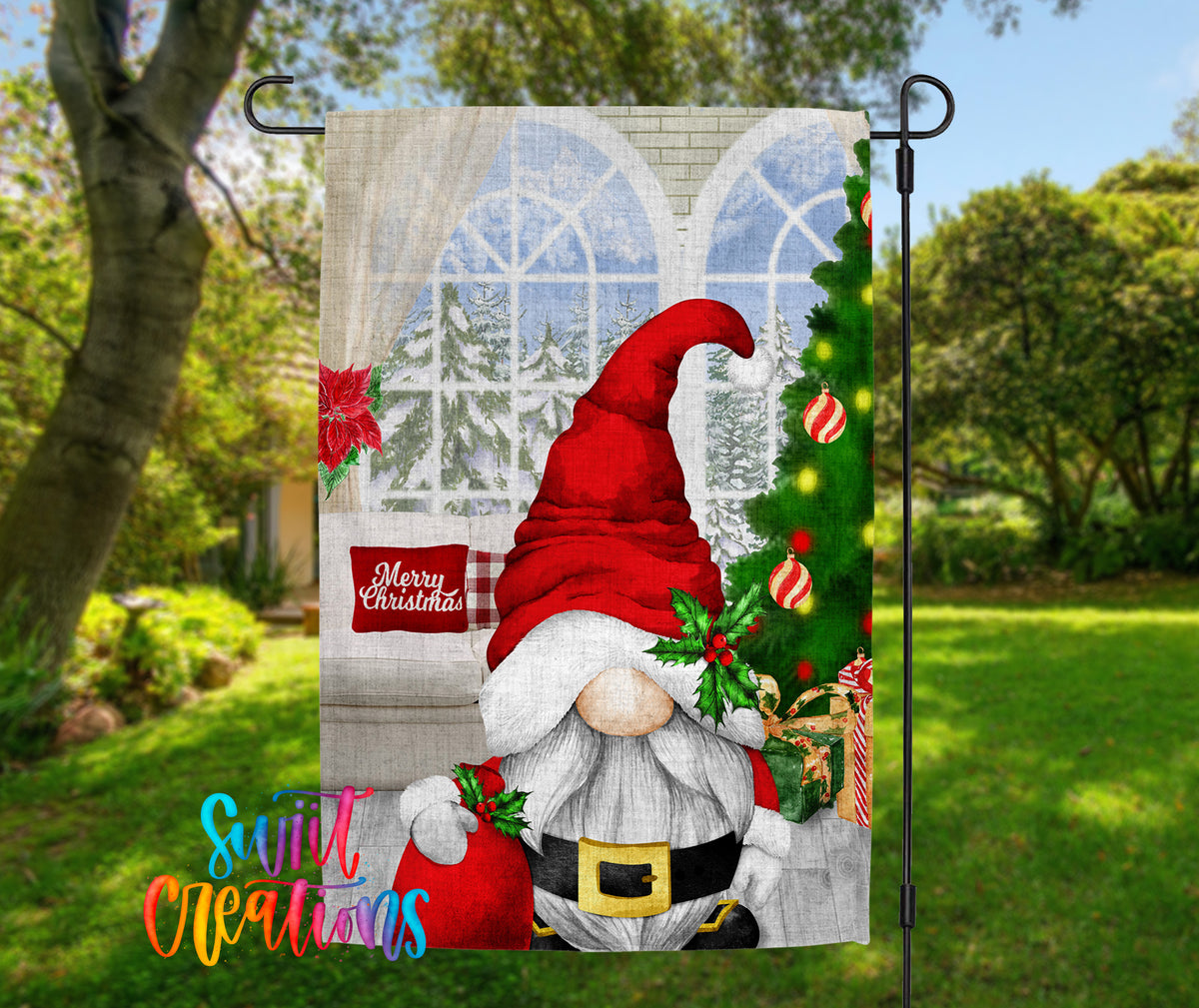 A Christmas-themed garden flag featuring a gnome wearing a Santa hat and holding a Christmas tree, with a "Merry Christmas" sign in the background.