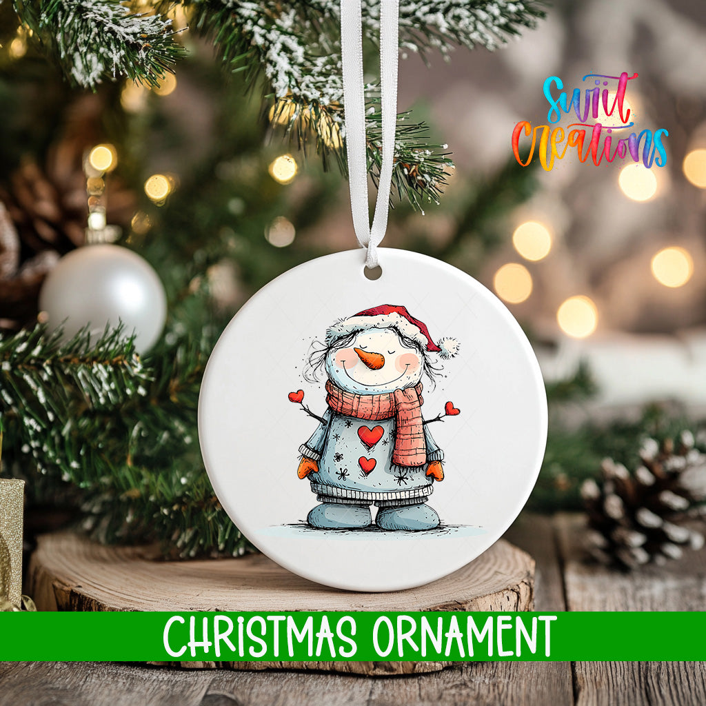 A white Christmas ornament featuring a snowman is hanging from a tree branch, with a blurred background of lights and greenery.