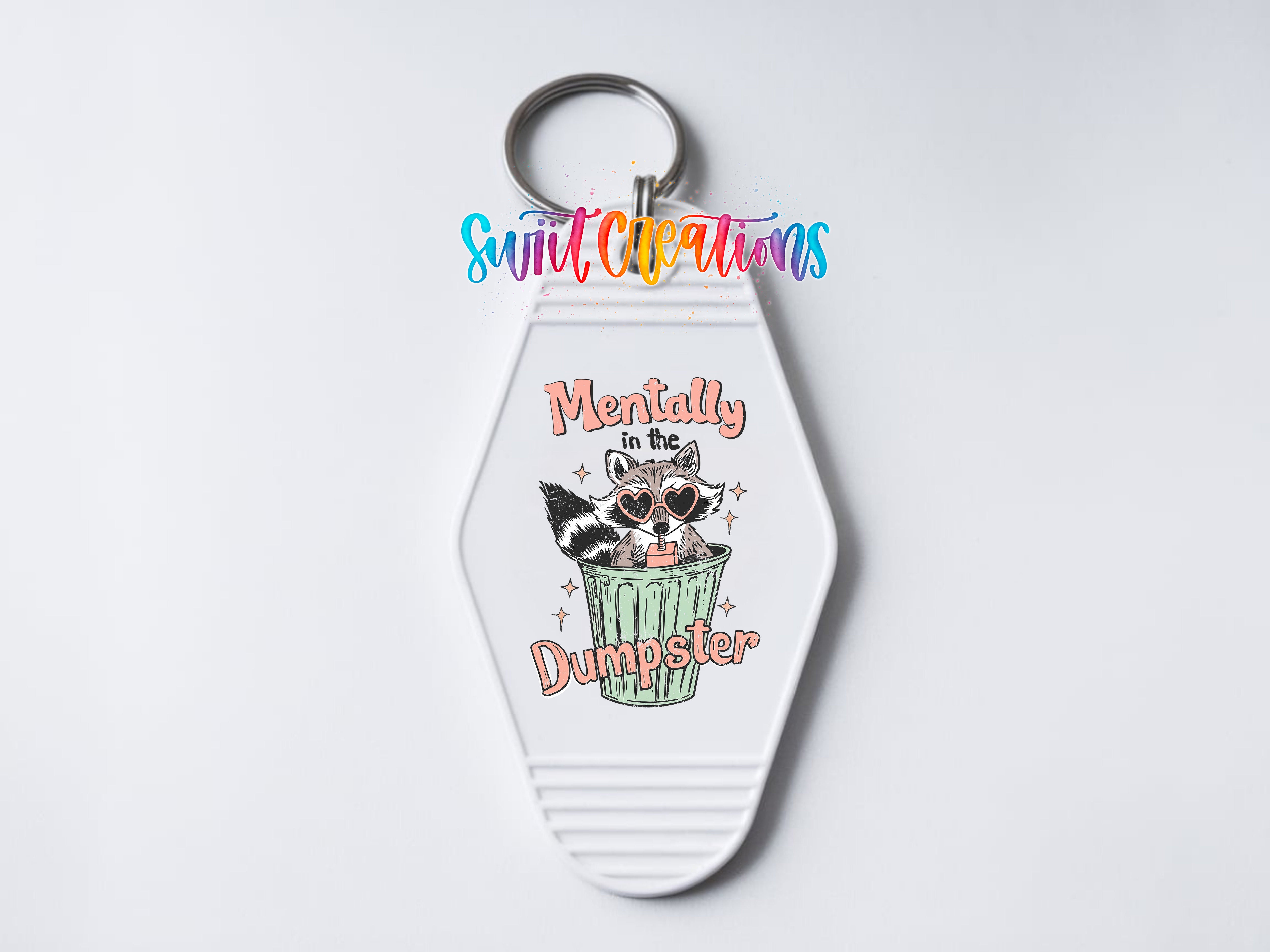 A keychain with a cartoon raccoon wearing sunglasses and the text "Mentally dumpster" printed on it.