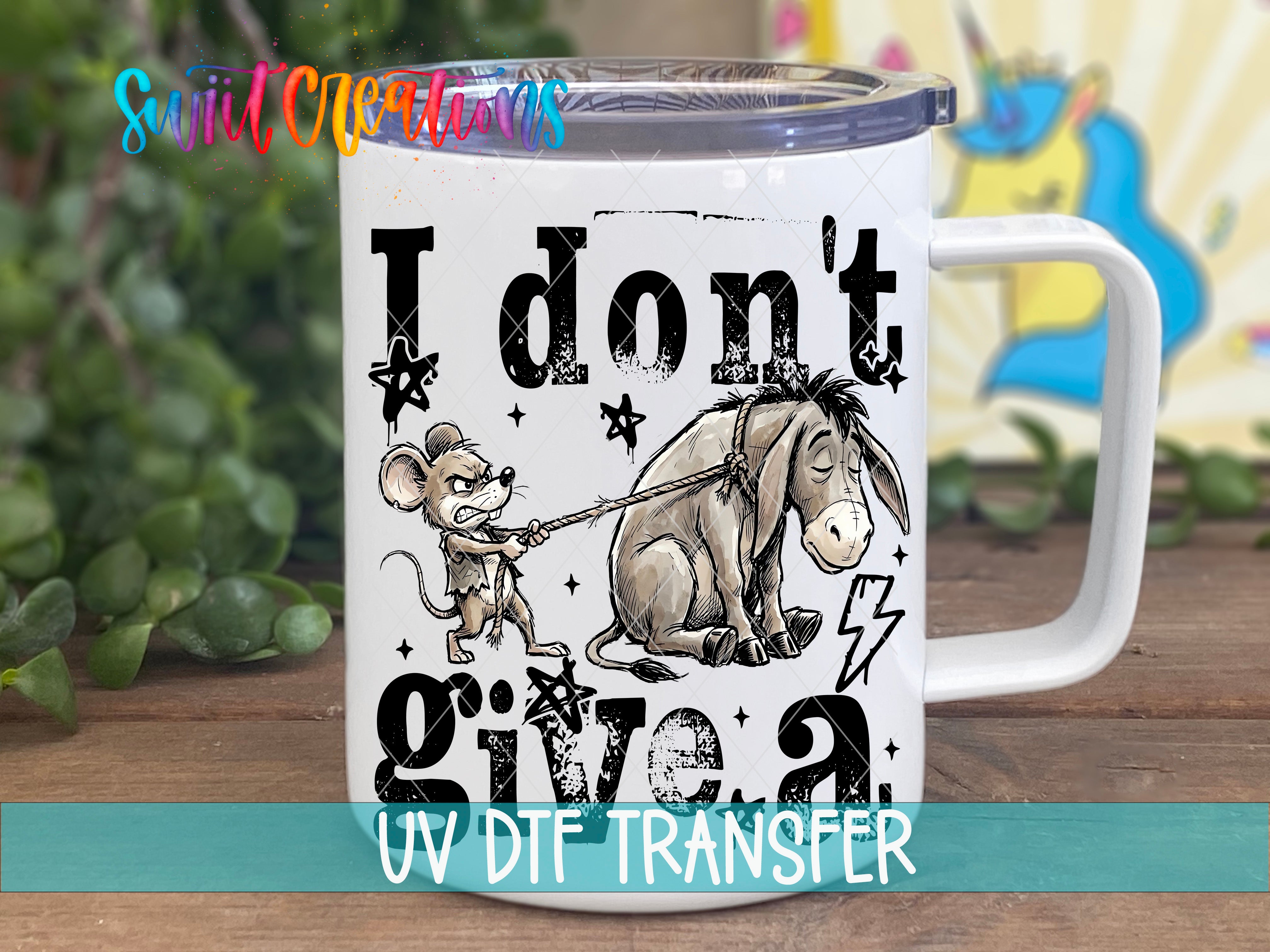 A white mug with a printed design featuring a cartoon mouse and a donkey, along with the text "I don't give a" and "UV DIF TRANSFER".