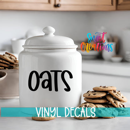 A white ceramic jar labeled "OATS" sits on a kitchen counter, with a stack of chocolate chip cookies nearby.