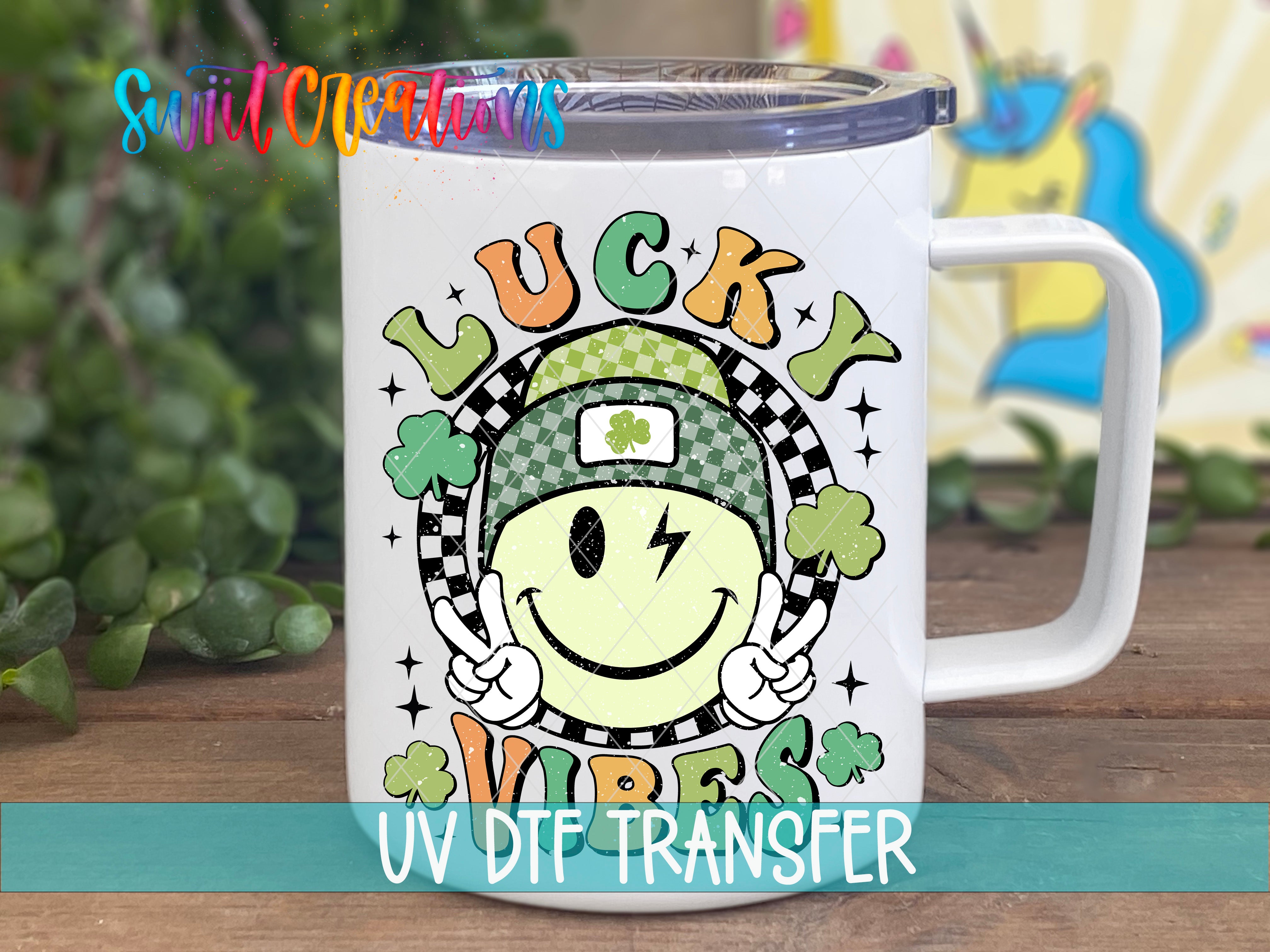 A white mug with a colorful design featuring a smiling face, a rainbow, and the text "Lucky Vibes" printed on it.