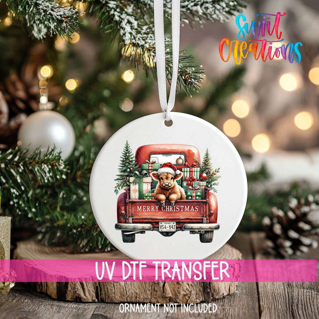 A white Christmas ornament with a red truck carrying a bear and presents, hanging on a tree.