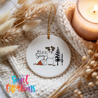 Let It Snow snowman winter forest ceramic Christmas ornament styled beside a candle and cozy knit blanket
