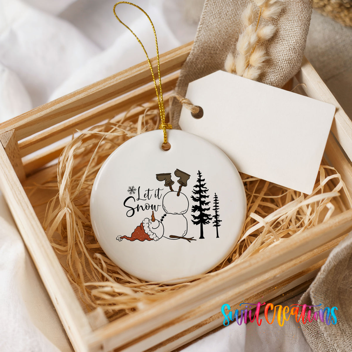 Let It Snow snowman winter forest ceramic Christmas ornament displayed in a rustic wooden gift crate