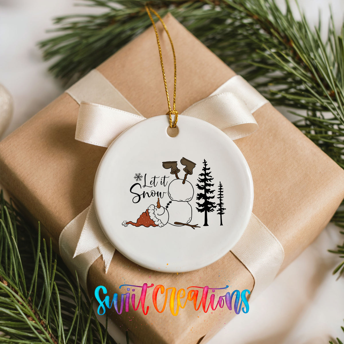 Let It Snow snowman winter forest ceramic Christmas ornament arranged on a wrapped Christmas gift