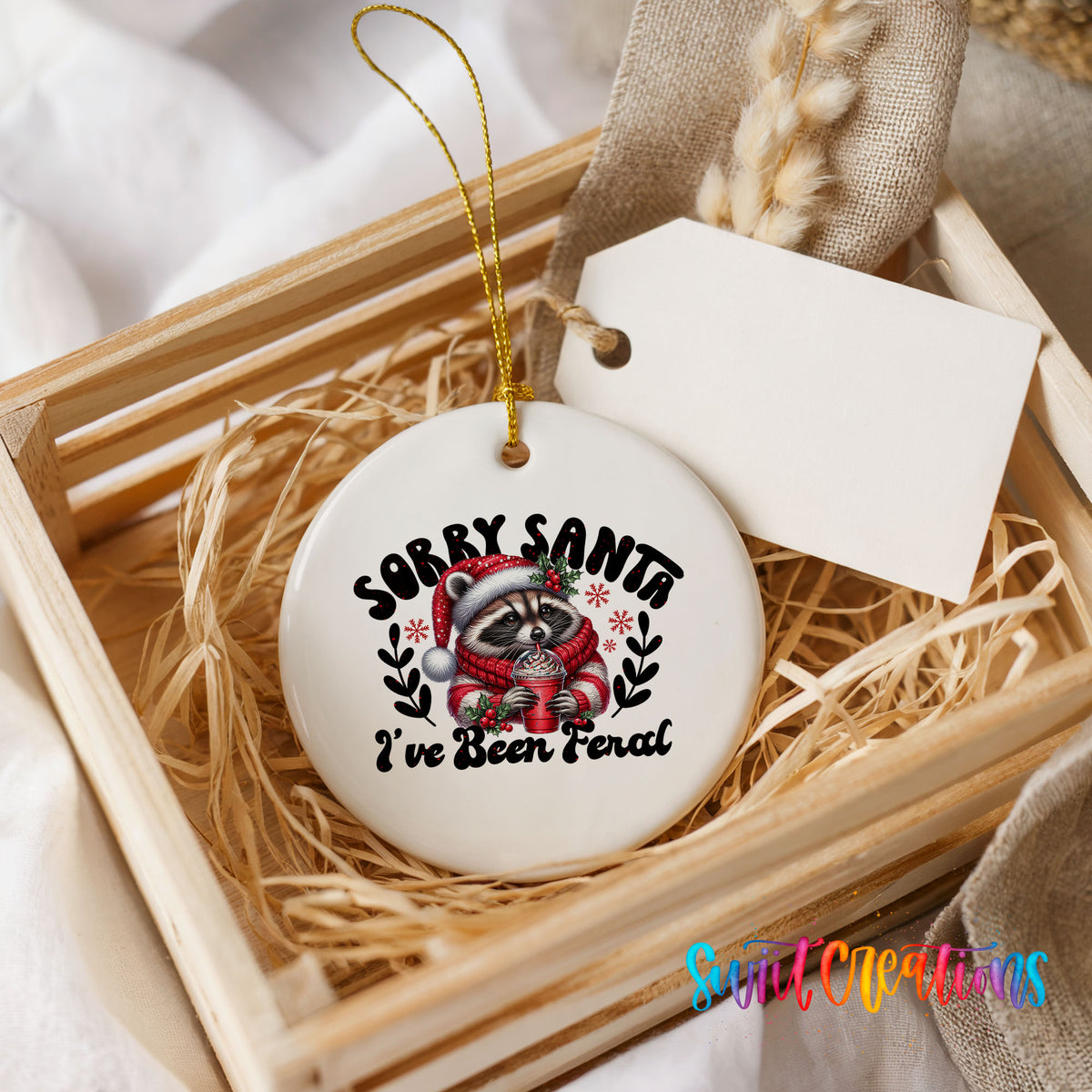 Sorry Santa I've Been Feral funny raccoon ceramic Christmas ornament displayed in a rustic wooden gift crate