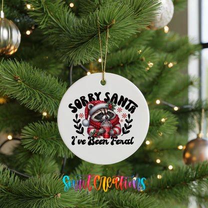Sorry Santa I've Been Feral funny raccoon ceramic Christmas ornament hanging on a green Christmas tree