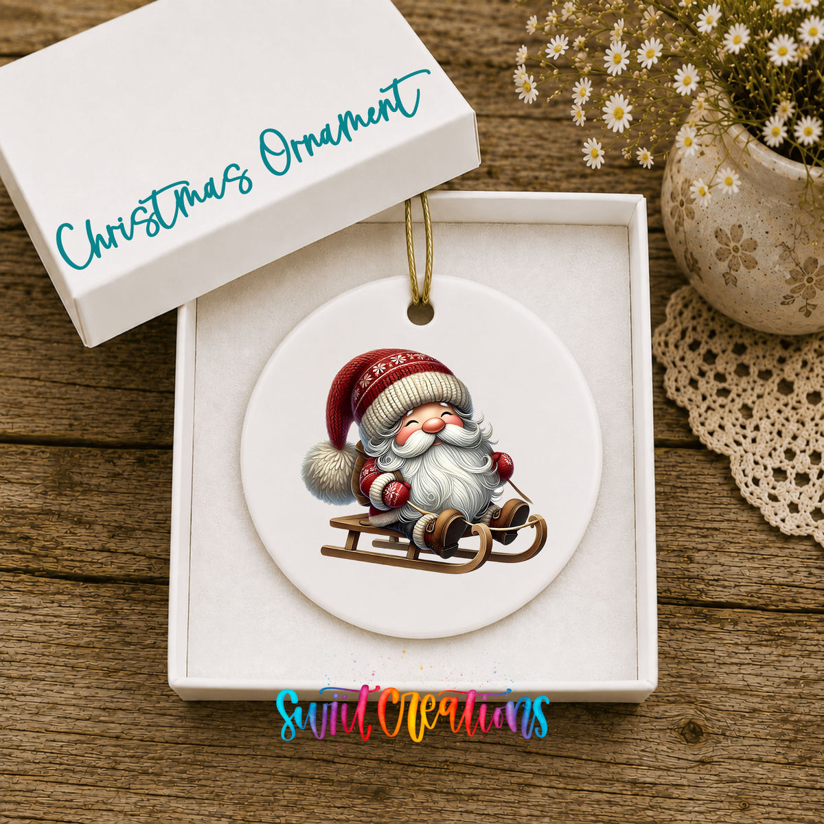 Sleeping Santa on a sled ceramic Christmas ornament displayed in the included gift box
