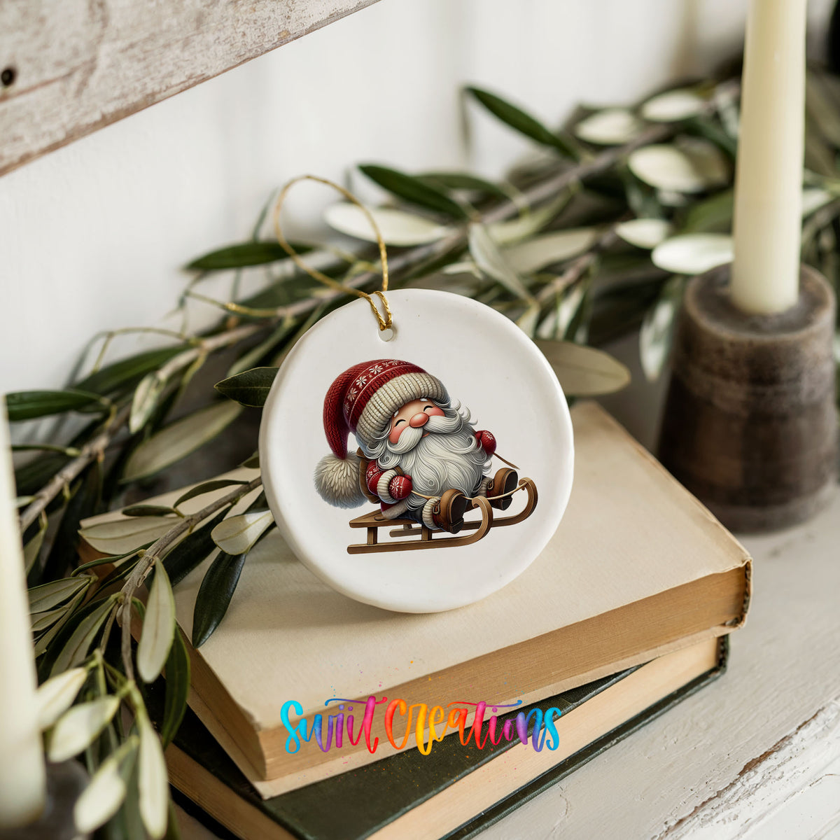 Sleeping Santa on a sled ceramic Christmas ornament styled on books with holiday greenery