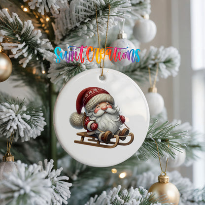 Sleeping Santa on a sled ceramic Christmas ornament hanging on a frosted Christmas tree
