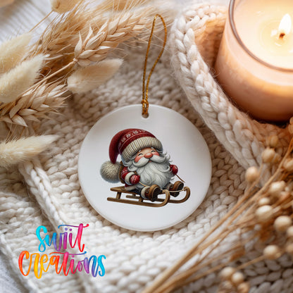 Sleeping Santa on a sled ceramic Christmas ornament styled beside a candle and cozy knit blanket