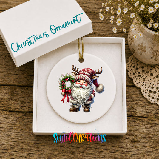 Cozy Santa holding a Christmas wreath ceramic ornament displayed in the included gift box