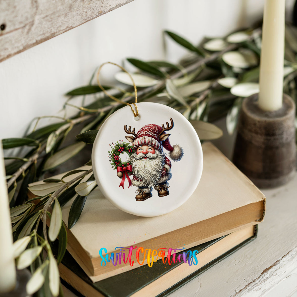 Cozy Santa holding a Christmas wreath ceramic ornament styled on books with holiday greenery