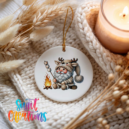 Santa roasting a marshmallow by a campfire ceramic Christmas ornament styled beside a candle and cozy knit blanket