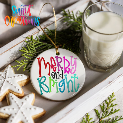 Round ceramic Christmas ornament featuring colorful hand-lettered Merry and Bright holiday typography, styled with cookies and milk