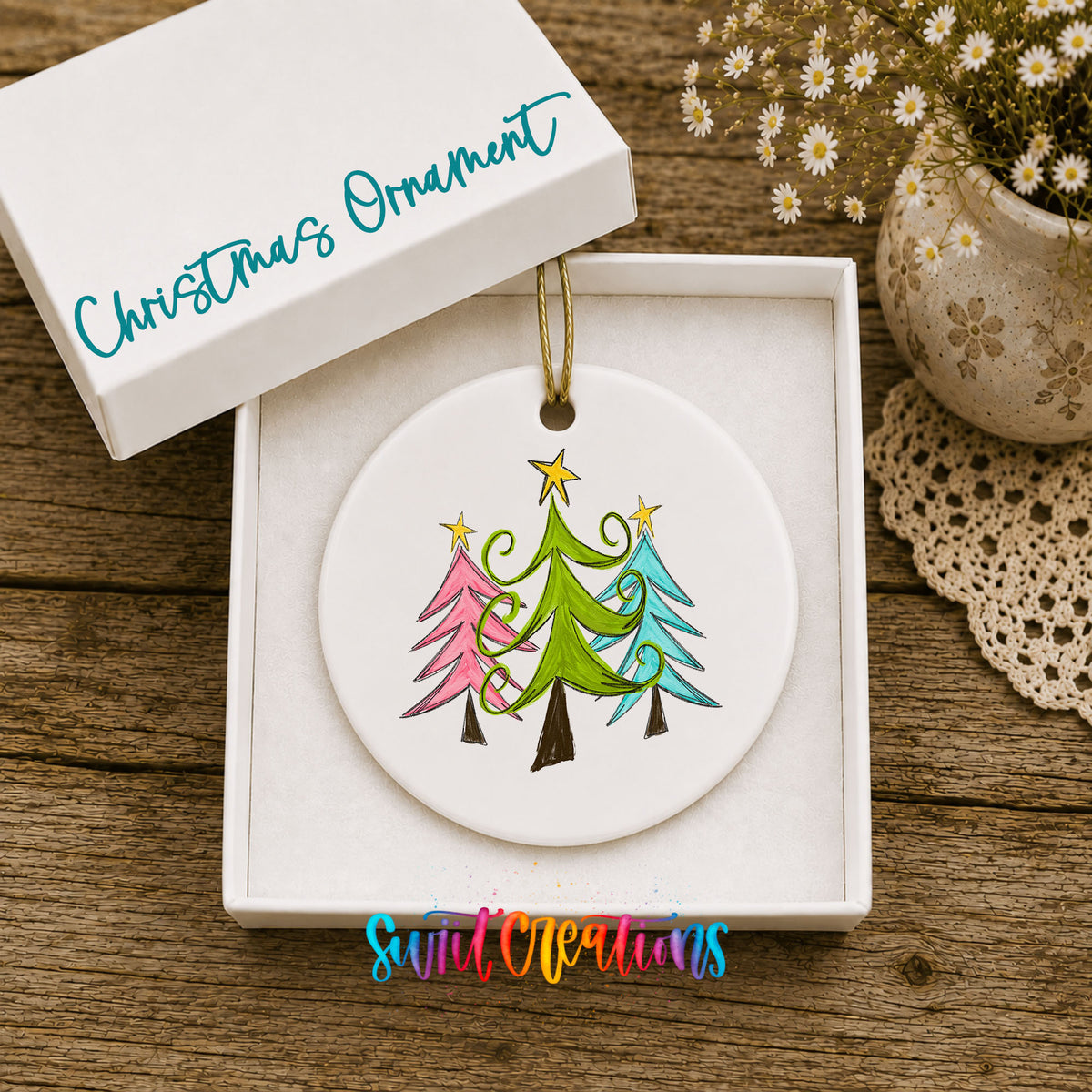Round ceramic Christmas ornament featuring three colorful whimsical Christmas trees, displayed in the included gift box