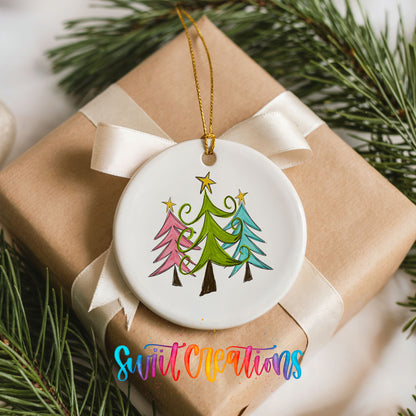 Round ceramic Christmas ornament featuring three colorful whimsical Christmas trees, placed on a wrapped Christmas gift