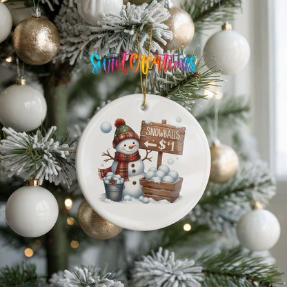 Round ceramic Christmas ornament featuring cheerful snowman selling snowballs for five cents, hanging on a frosted holiday tree