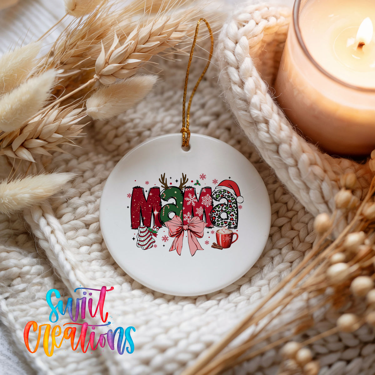 Round ceramic Christmas ornament featuring festive patterned Mama lettering with a large red holiday bow, styled beside a candle and cozy knit blanket