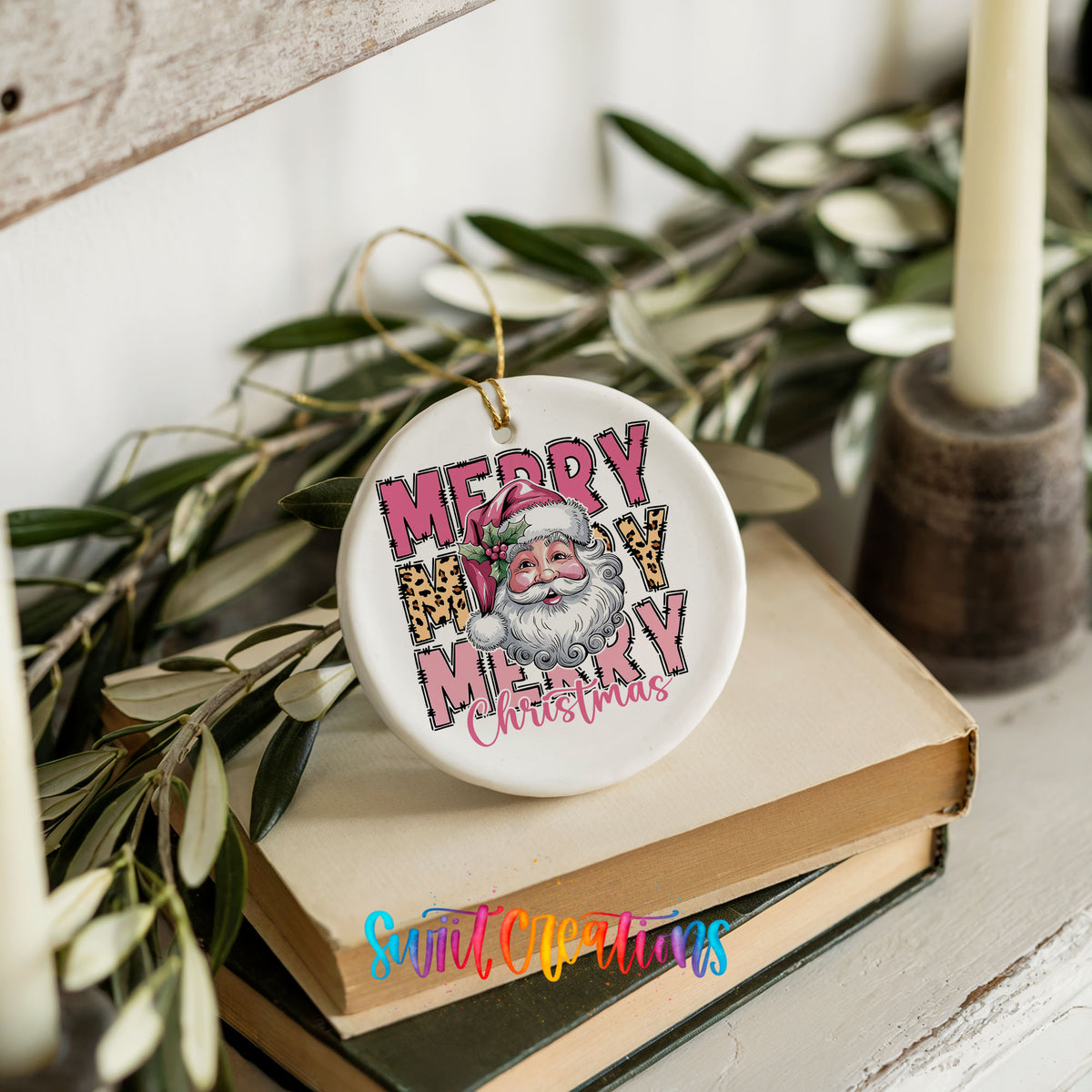Round ceramic Christmas ornament featuring stacked Merry Merry Merry Christmas lettering with Santa and leopard print accents, styled on books with holiday greenery