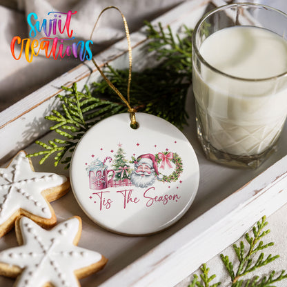 Round ceramic Christmas ornament featuring vintage Santa with floral greenery and ’Tis the Season lettering, styled with cookies and milk