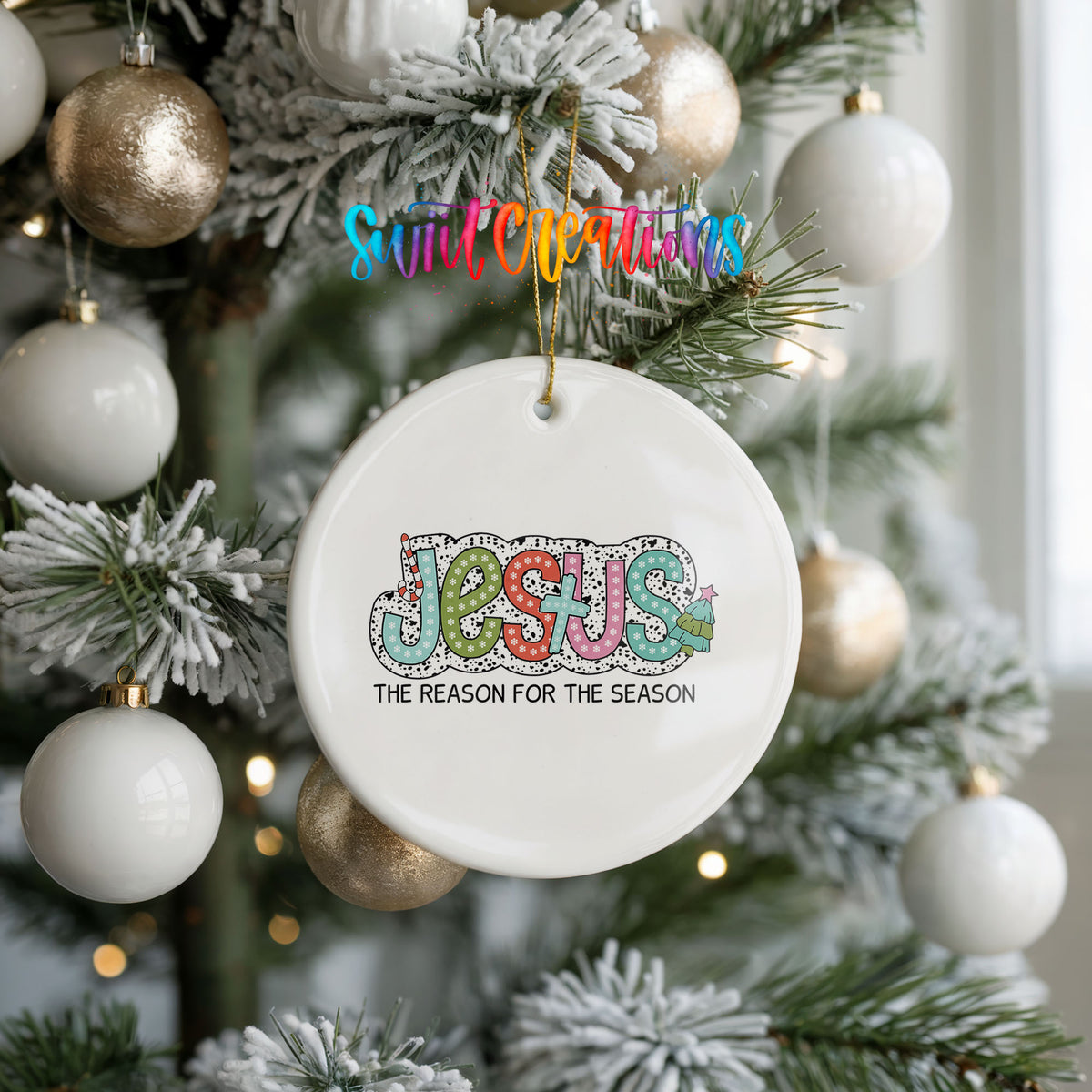 Round ceramic Christmas ornament featuring colorful Jesus Is the Reason for the Season typography, hanging on a frosted holiday tree