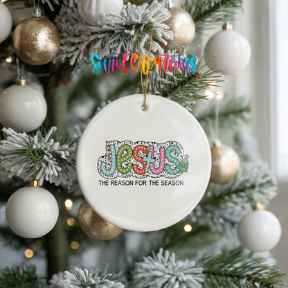 Round ceramic Christmas ornament featuring colorful Jesus Is the Reason for the Season typography, hanging on a frosted holiday tree