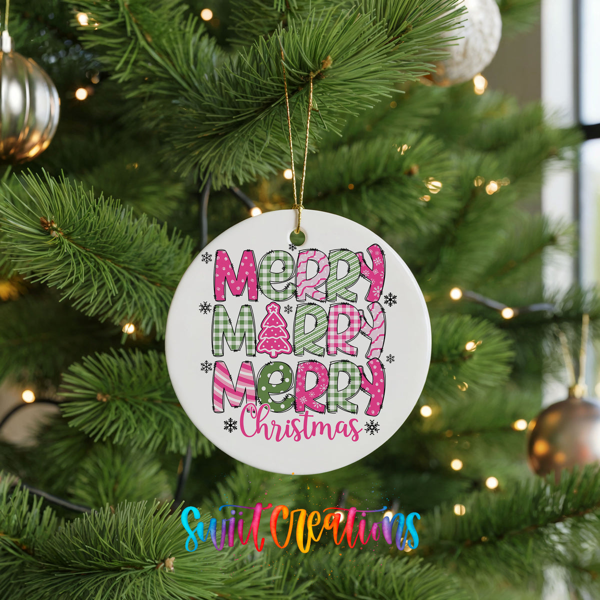 Round ceramic Christmas ornament featuring stacked patterned Merry Merry Merry Christmas lettering in pink and green, hanging on a green Christmas tree