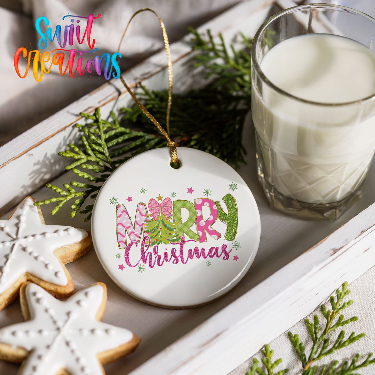 Round ceramic Christmas ornament featuring bright Merry Christmas lettering with candy stripe and floral details, styled with cookies and milk