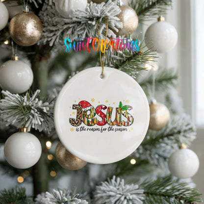 Round ceramic Christmas ornament featuring colorful Jesus Is the Reason for the Season typography, hanging on a frosted holiday tree