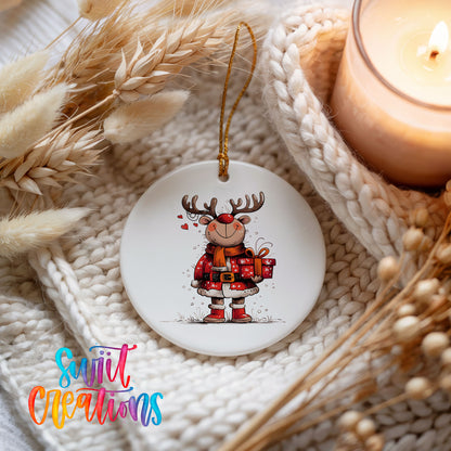Round ceramic Christmas ornament featuring cheerful reindeer in a Santa suit holding wrapped Christmas gifts, styled beside a candle and cozy knit blanket