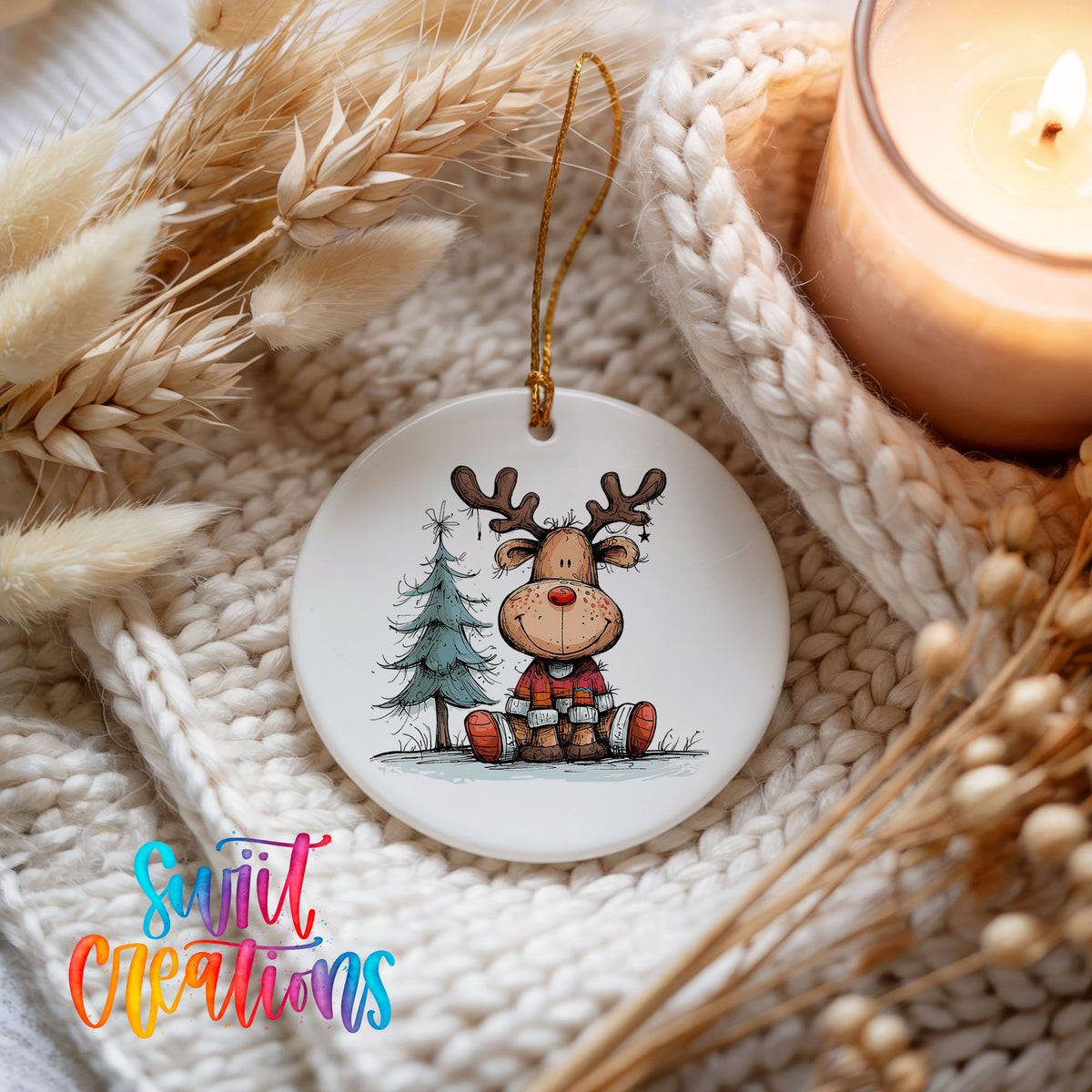 Sitting Reindeer with Pine Trees and Gift Christmas ornament styled beside a candle and cozy knit blanket