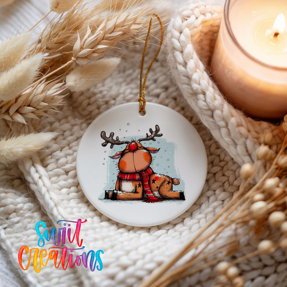 Santa and Reindeer with Gift Sack Christmas ornament styled beside a candle and cozy knit blanket