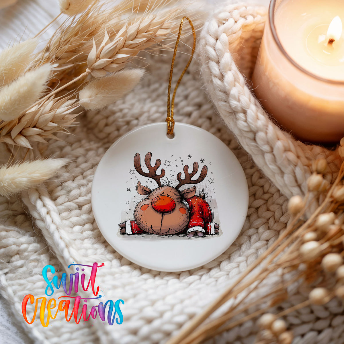Sleeping Reindeer in Red Scarf Christmas ornament styled beside a candle and cozy knit blanket