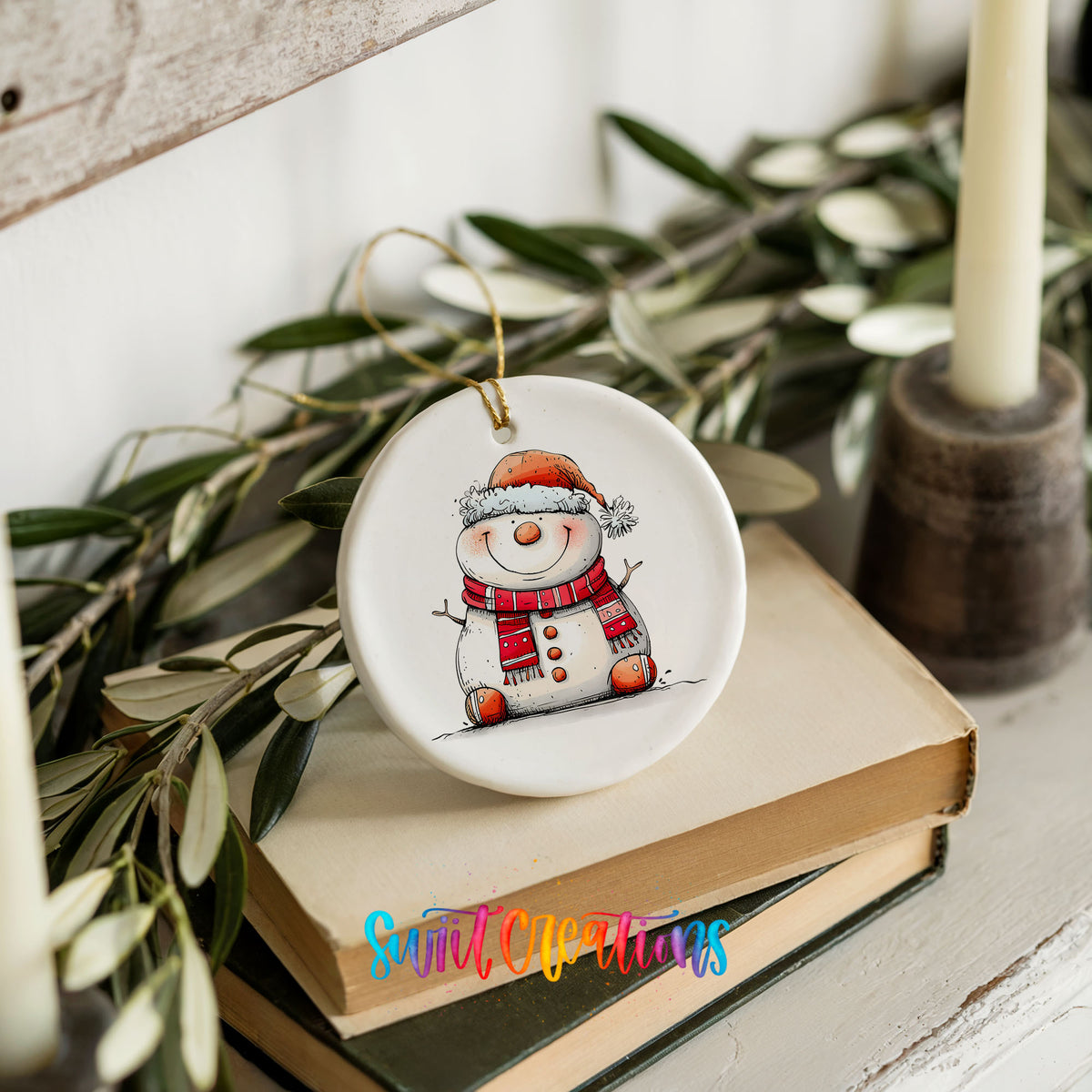 Cheerful Snowman in Santa Hat Christmas ornament styled on books with holiday greenery