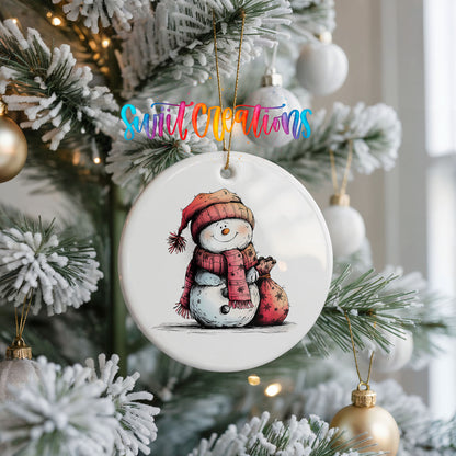 Snowman in Red Scarf with Gift Christmas ornament hanging on a frosted Christmas tree