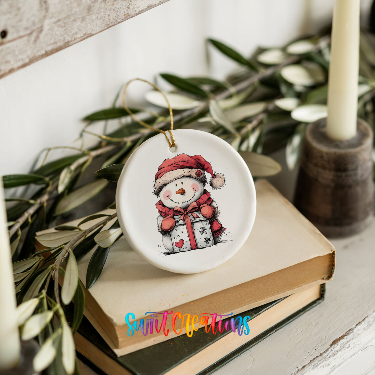 Snowman with Wrapped Christmas Gift Christmas ornament styled on books with holiday greenery