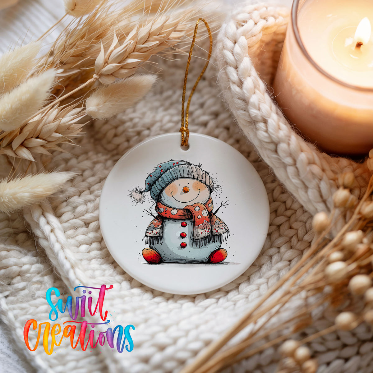 Snowman in Red Hat and Blue Scarf Christmas ornament styled beside a candle and cozy knit blanket