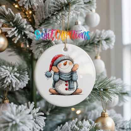 Snowman in Blue Hat and Scarf Christmas ornament hanging on a frosted Christmas tree